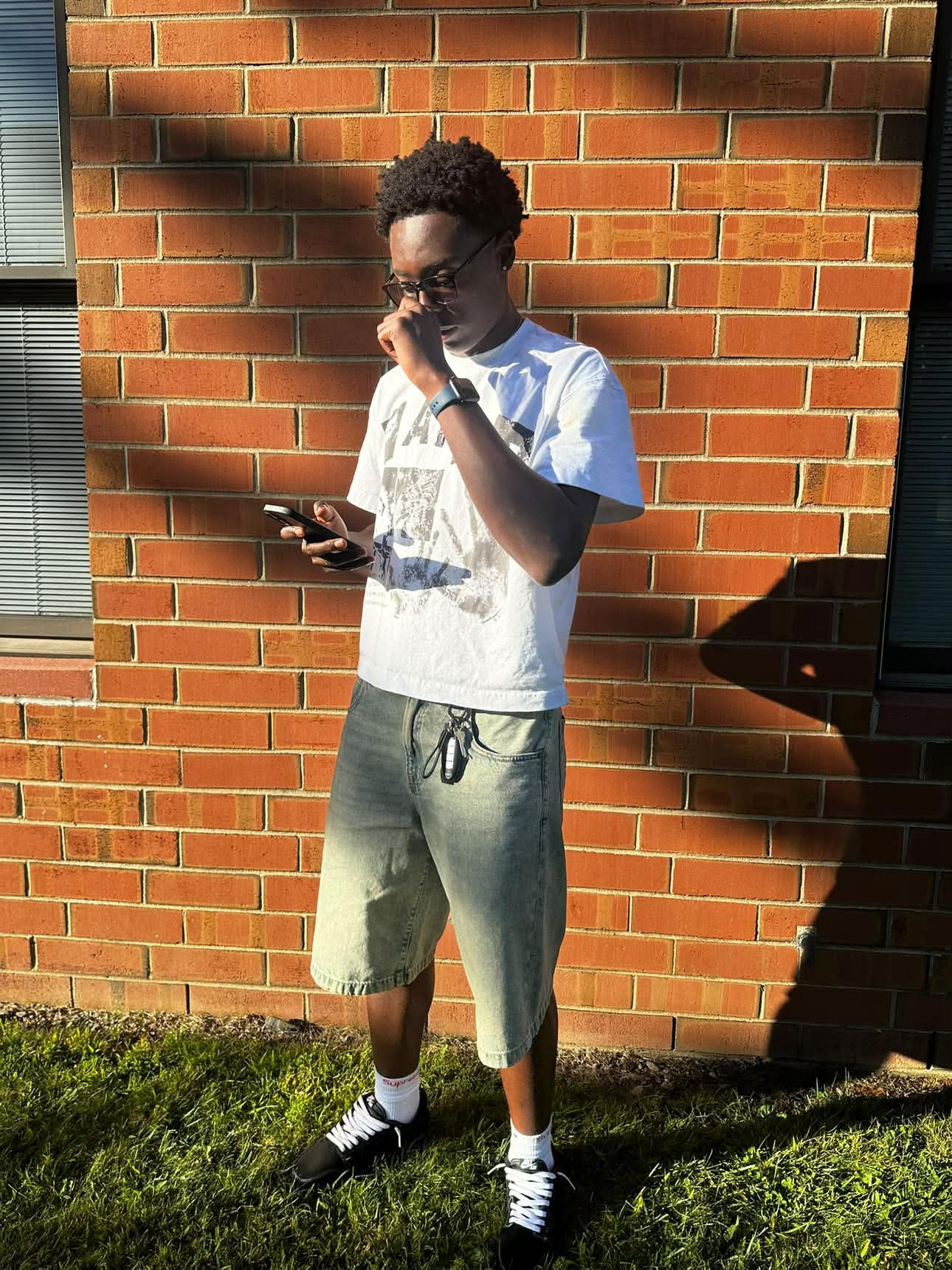 Model in the white Faith graphic tee by a brick wall